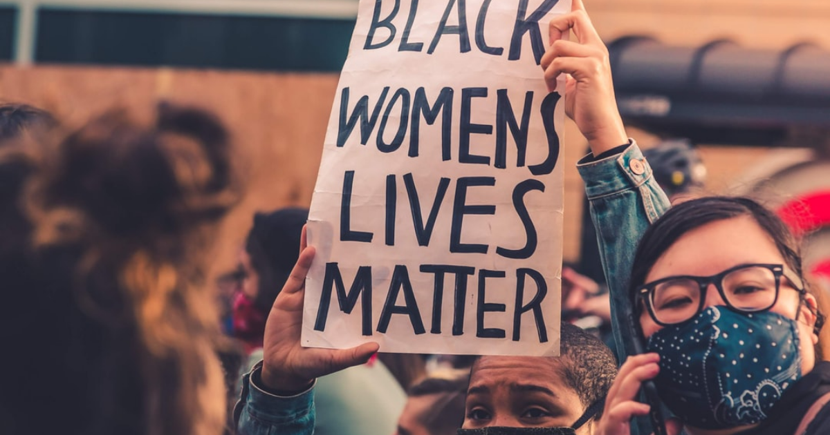 A protestor holds up a "Black Women's Lives Matter" sign
