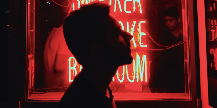 Silhouette of a man's face in front of red neon signage