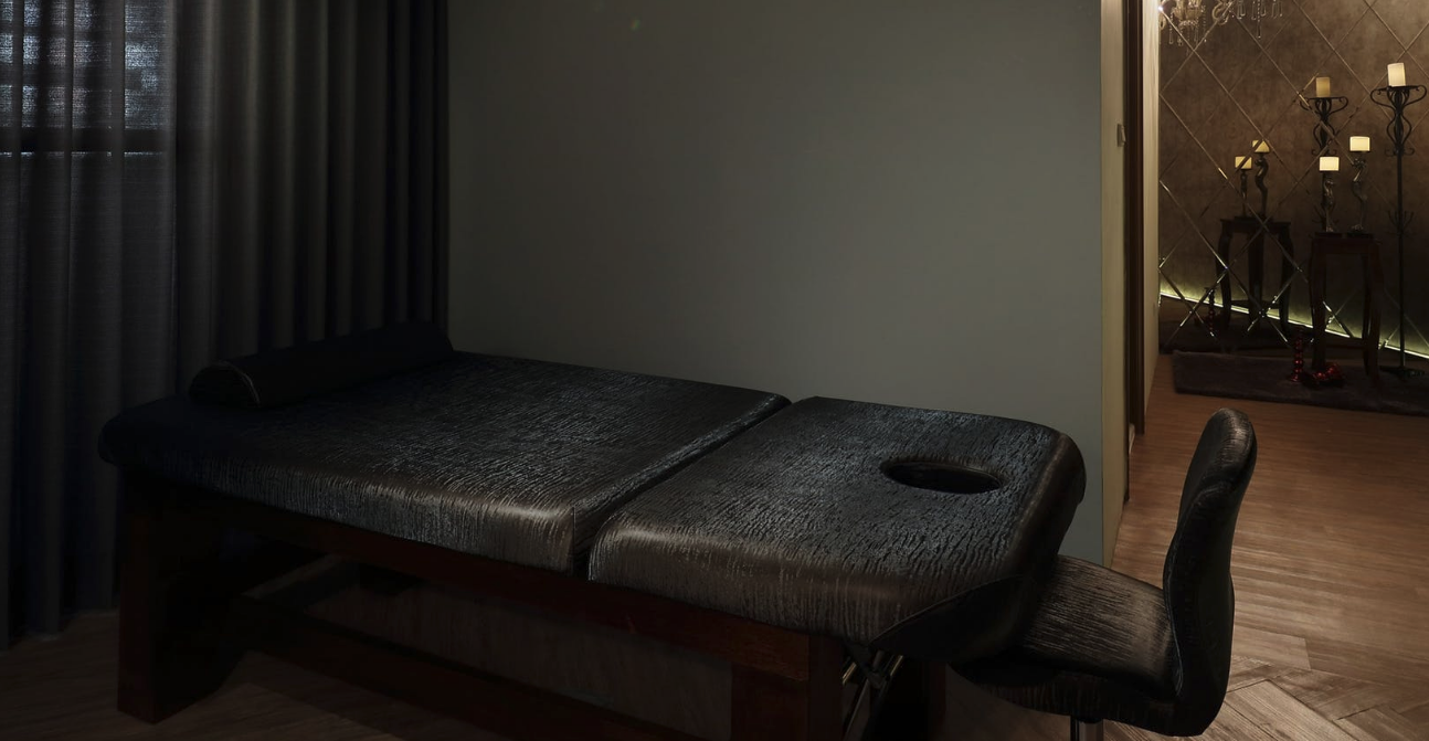 Empty massage table in dim room (symbolic of Massage Envy's abandonment of customer safety)