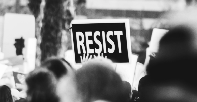 Still of someone holding a sign that says "Resist" as a representation of the fight to end sexual exploitationCover of the 2019 NCOSE Impact Report